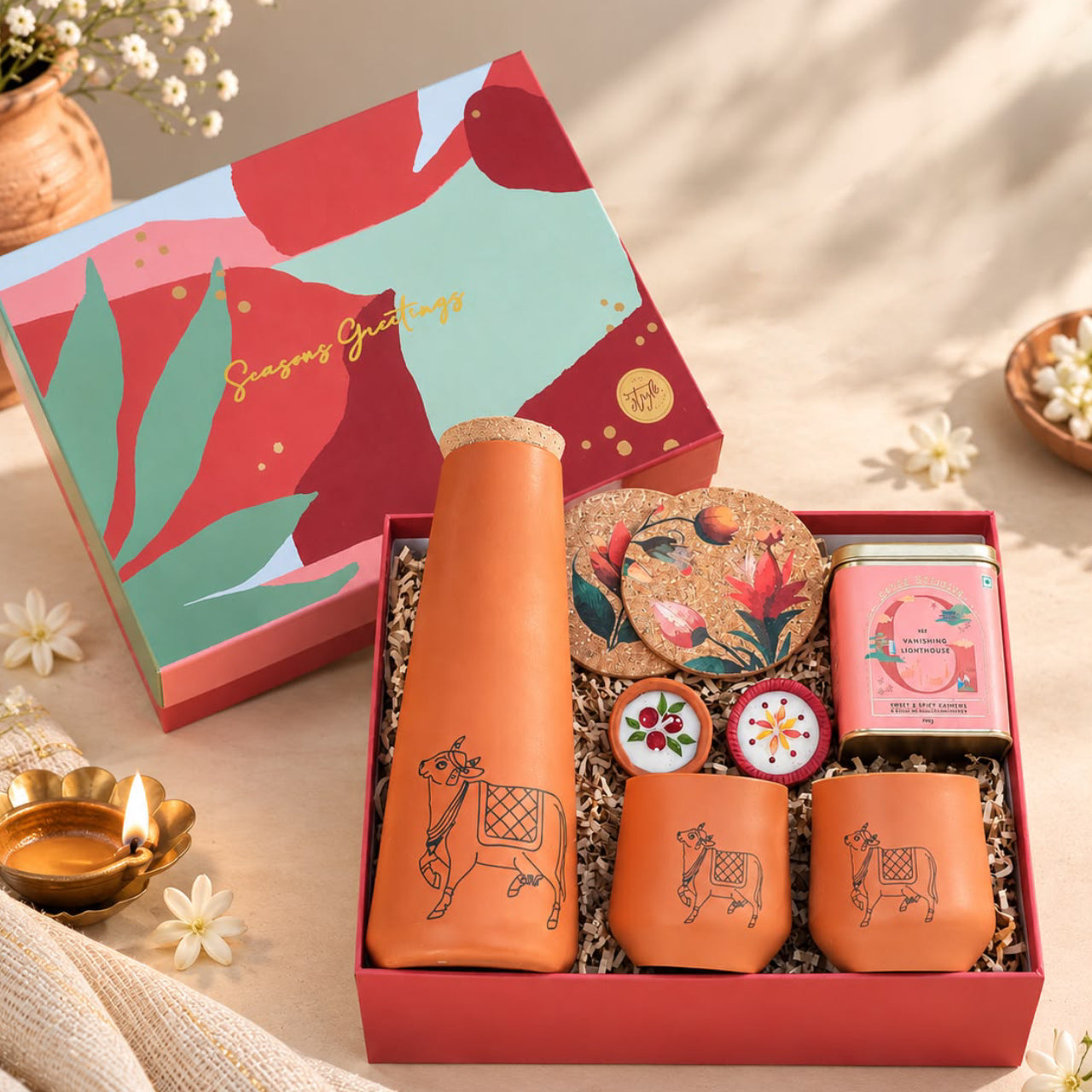 Corporate festive gift box with Kapila bottle and glass, Flora cork coaster set, sweet and spicy cashews and handcrafted Diwali diyas