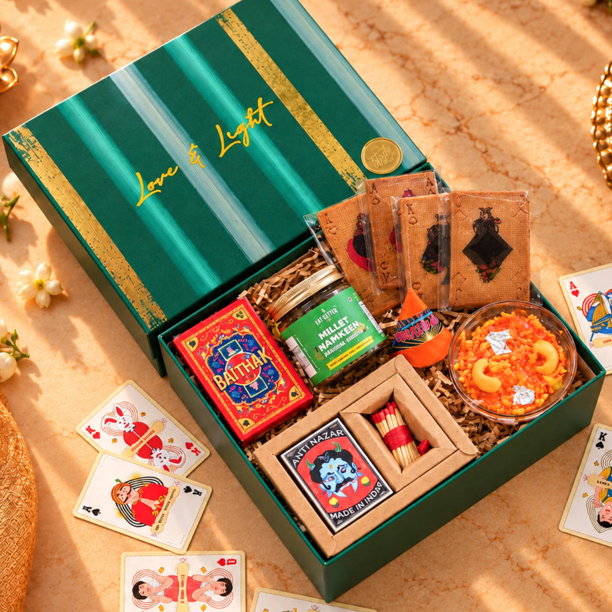 Pataka Pop Diwali gift hamper with Baithak playing cards, plantable seed crackers, gajar halwa candle, millet namkeen and wooden matchbox